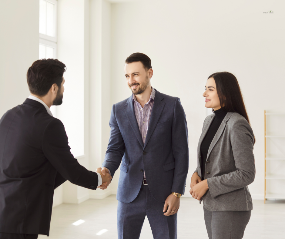 A professional estate agent in a dark suit warmly shaking hands with a smiling male client while a woman stands beside them in a bright, modern office. The scene reflects trust, professionalism, and excellent customer service, representing Integra Estates’ commitment to helping clients buy and sell property in Beckenham, Bromley, and across South East London.