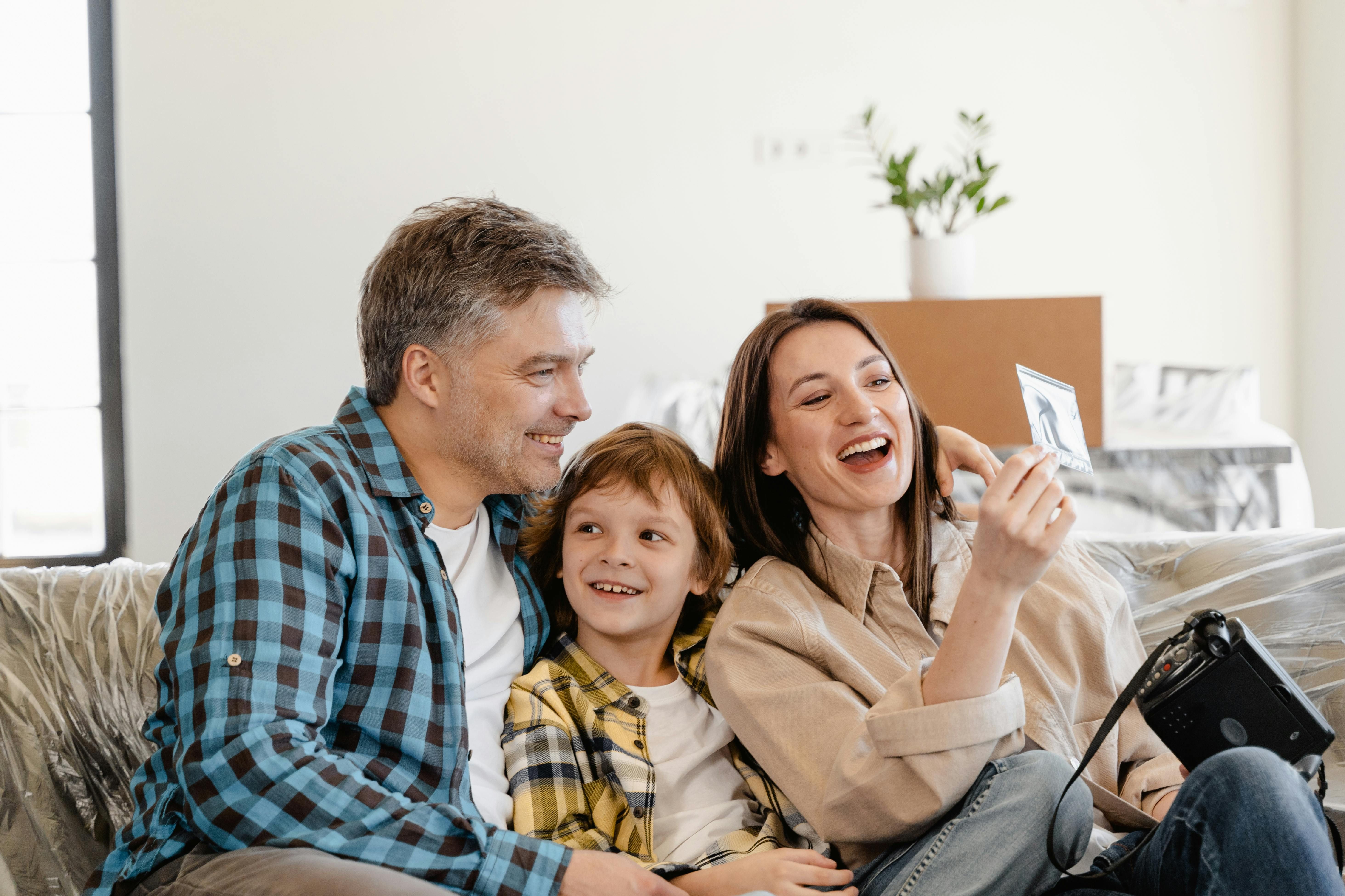 a happy family on teh sofa looking at a picture.