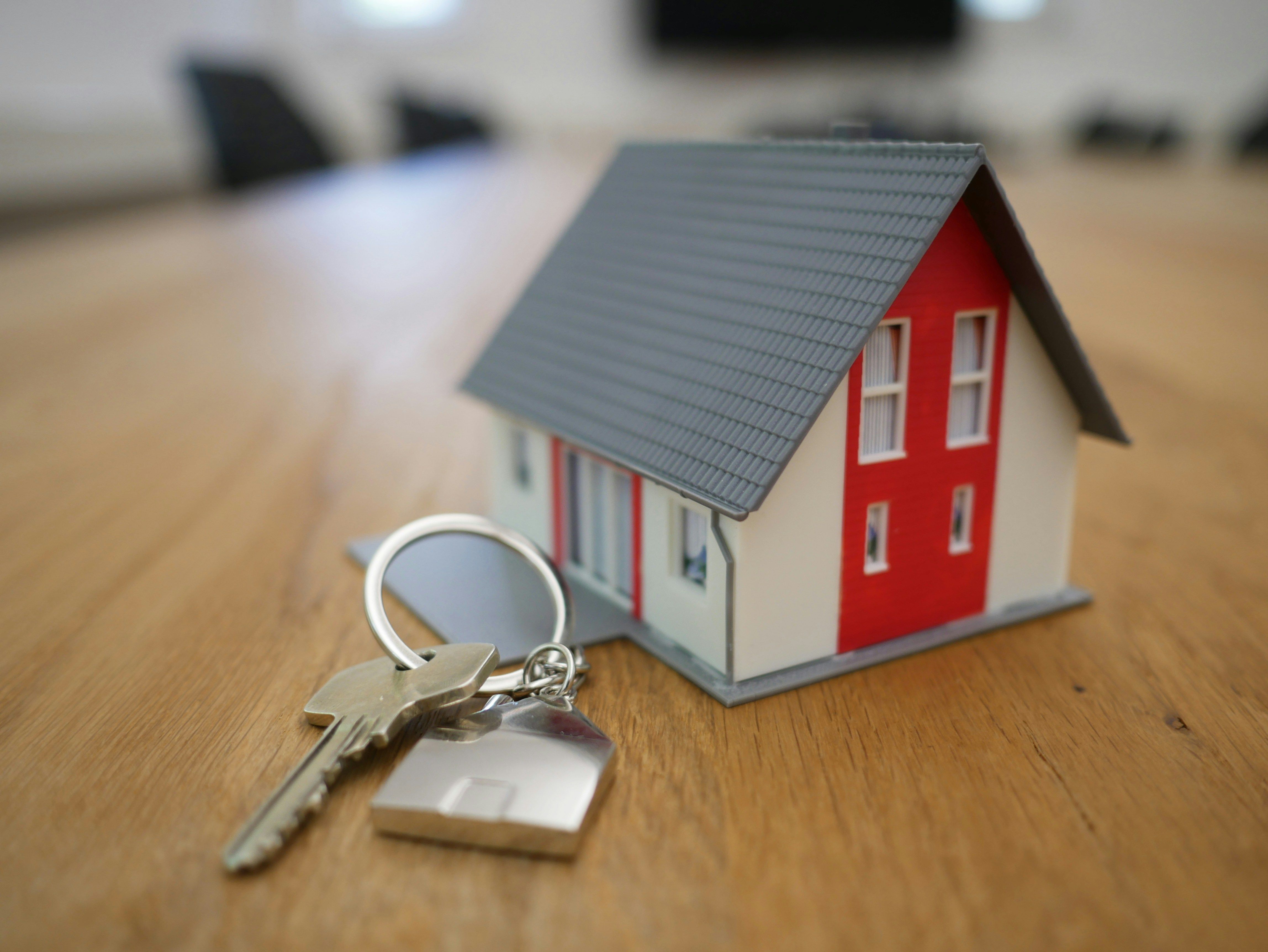 A miniature house with a red door with a key next to it.