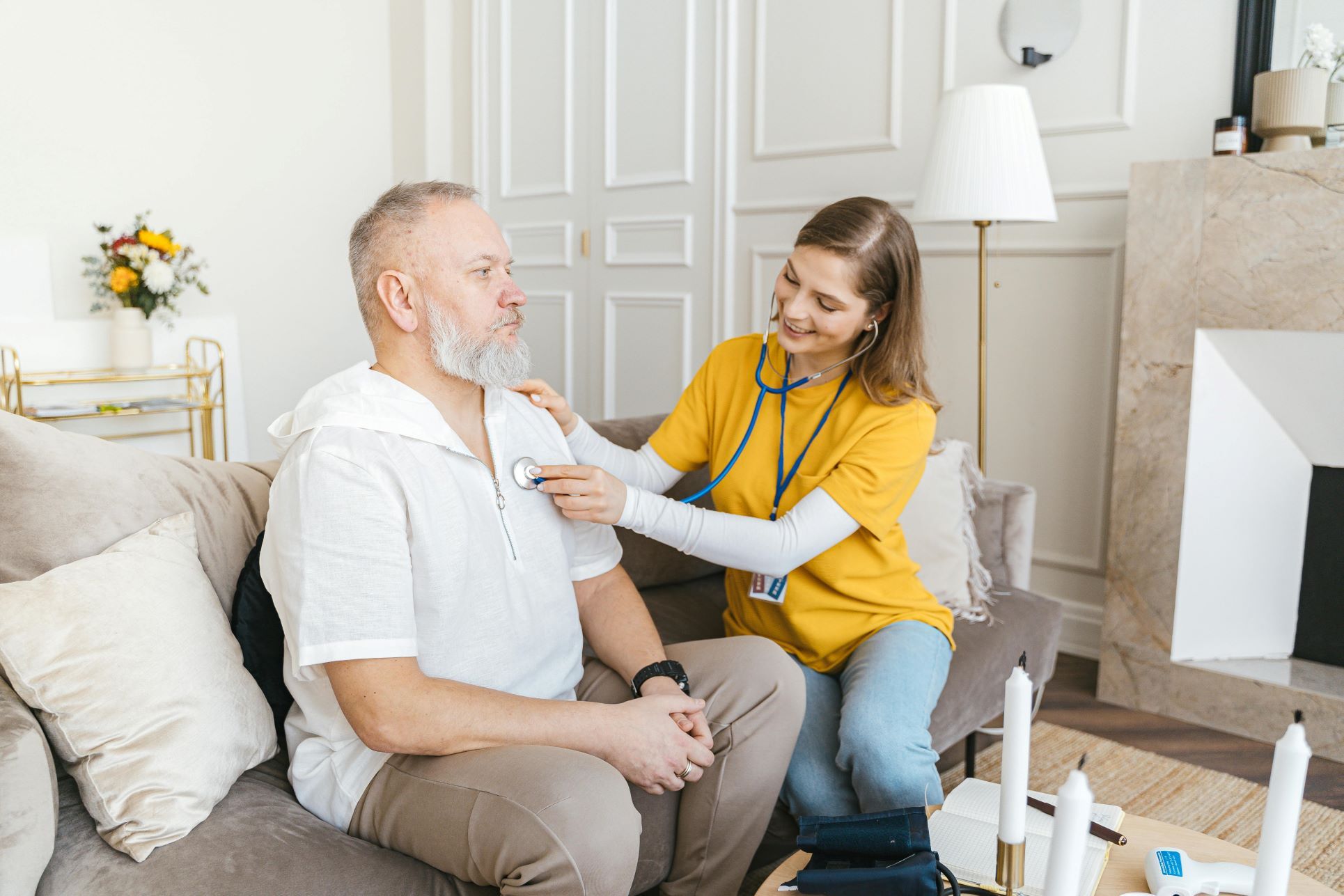 A caring healthcare professional providing home care in Orpington. The image shows a smiling nurse or carer checking an elderly man’s chest with a stethoscope, highlighting the importance of health services, assisted living, and community care in the local area. The relaxed setting with neutral décor, soft furnishings, and natural light reflects the comfort and dignity of receiving support at home. Perfect for SEO targeting Orpington care homes, assisted living, elderly support, and healthcare services in South East London.