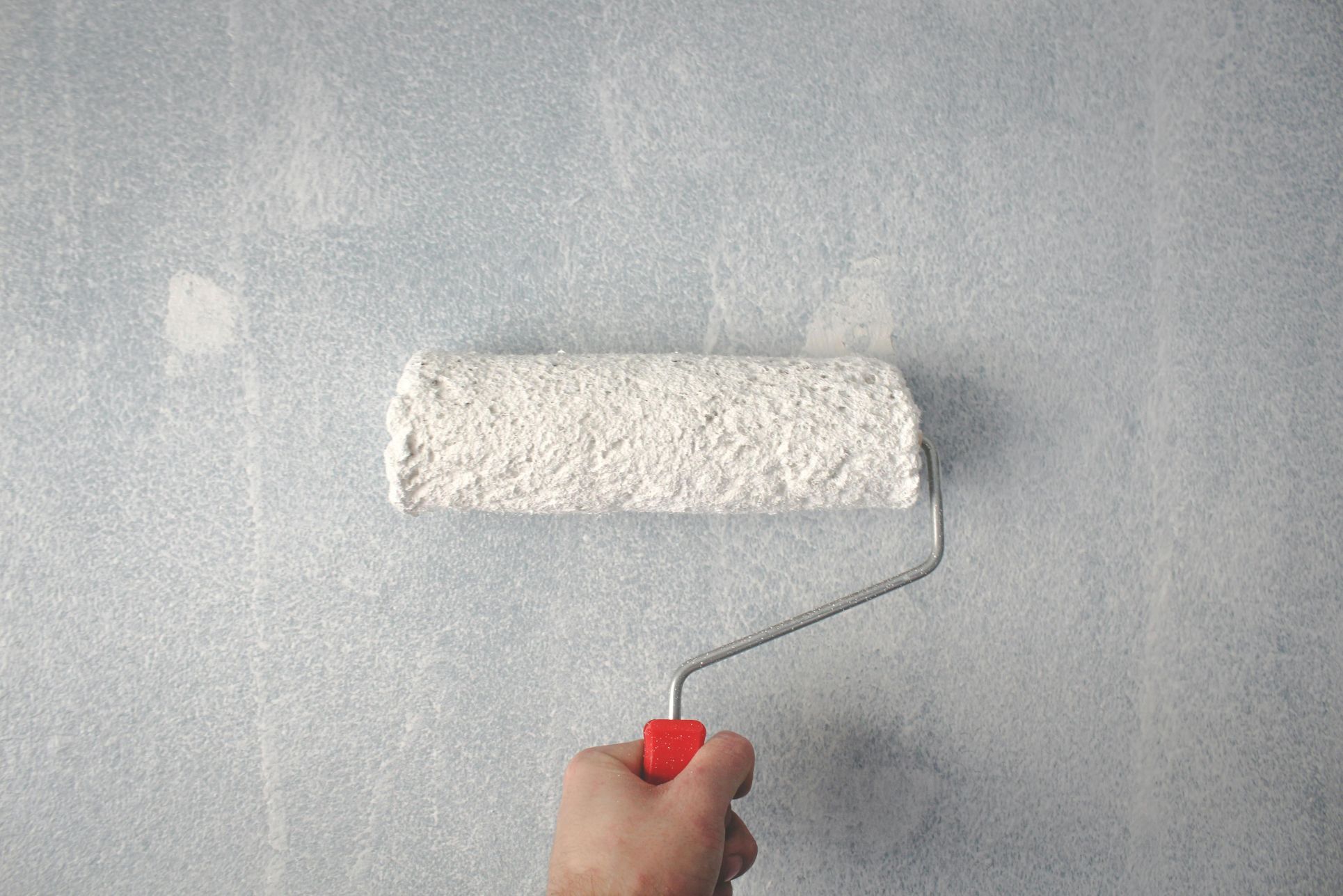 A homeowner applying fresh white paint to a wall with a roller, representing simple but effective home improvements when preparing to sell a property. The image highlights the importance of presentation and small upgrades to boost property appeal in the Orpington housing market. Ideal for SEO targeting preparing a house for sale Orpington, home improvements to sell property, Orpington estate agents, and boosting property value before selling.