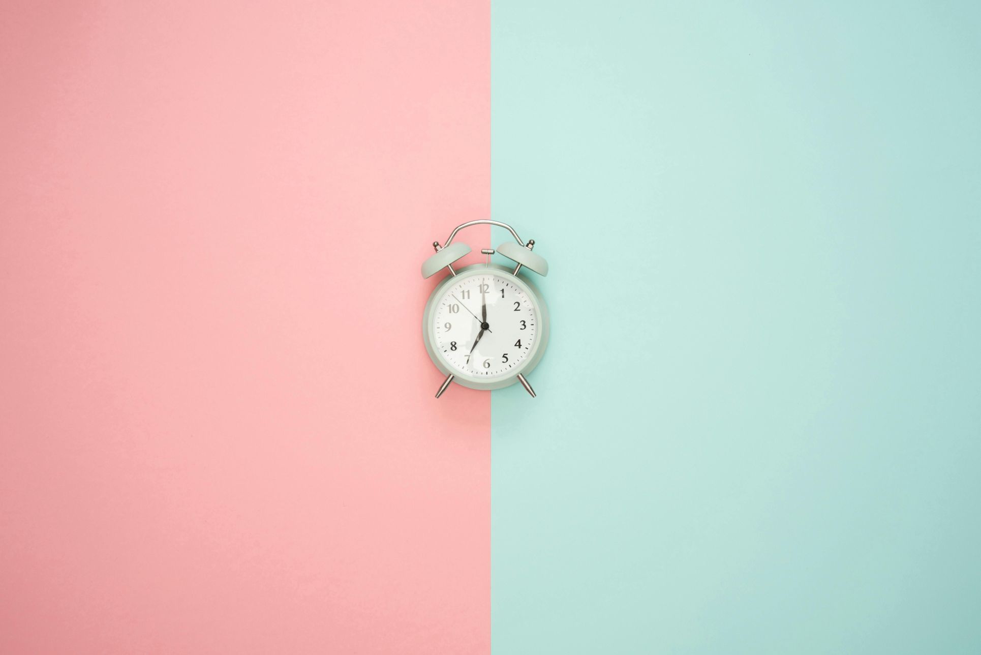 A minimalist image of a classic alarm clock placed at the centre of a pastel pink and blue background, representing timing and decision-making. Ideal for estate agent blogs discussing the best time to sell a home, market timing in Orpington, Beckenham, and South East London, or probate-related property sales where choosing the right moment matters.