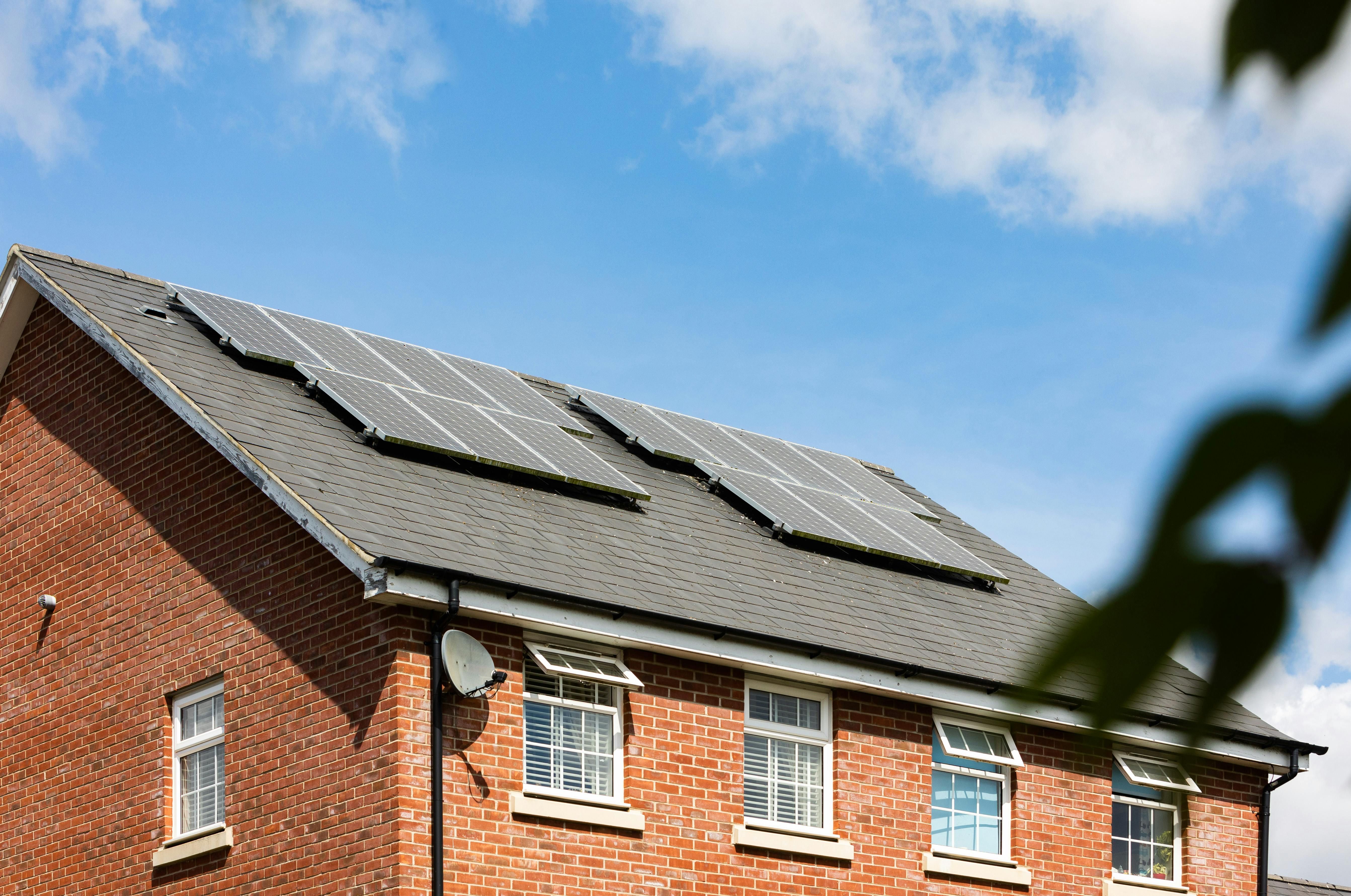 A modern red-brick home featuring rooftop solar panels against a bright blue sky. This eco-friendly property highlights renewable energy, sustainable living, and the increasing appeal of solar-powered homes in today’s housing market. Ideal for estate agent marketing with Integra Estates.